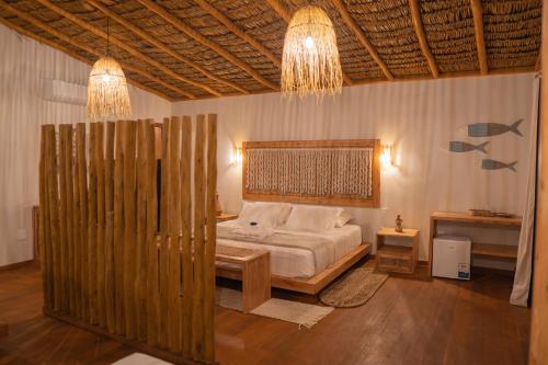 a bedroom with a bed with a wooden headboard at Rancharia Charme Beach - Pé na Areia in Atins
