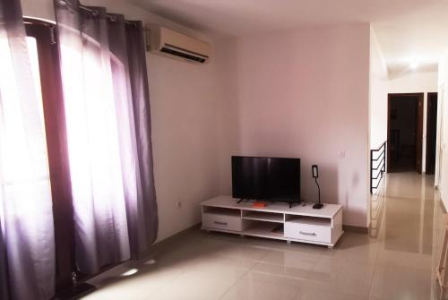 a living room with a tv on a cabinet with curtains at Miras Guest House in Praia