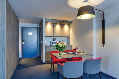 a kitchen with a table with red chairs and a blue door at Van der Valk Hotel Li&egrave;ge Congres in Li&egrave;ge