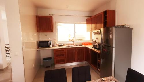 a kitchen with wooden cabinets and a stainless steel refrigerator at Miras Guest House in Praia