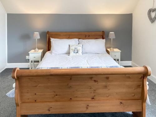 a bedroom with a large wooden bed with two lamps at Halleaths Home Farm in Lochmaben