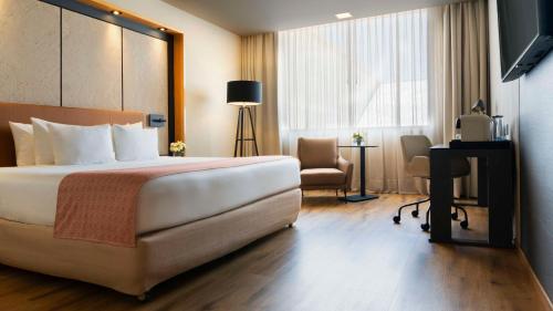 una camera d'albergo con un grande letto e una scrivania di NH Collection Mexico City Airport T2 a Città del Messico