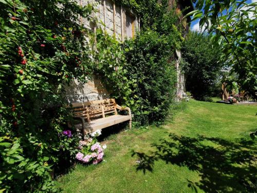 a wooden bench sitting in a garden with flowers at Fewo Hohe Liebe in Rathmannsdorf
