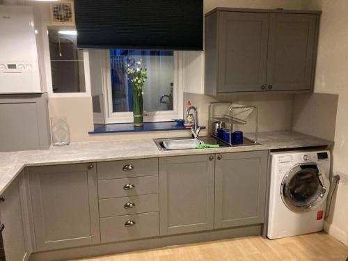 a kitchen with a sink and a washing machine at Lawn View Apartment in Dawlish
