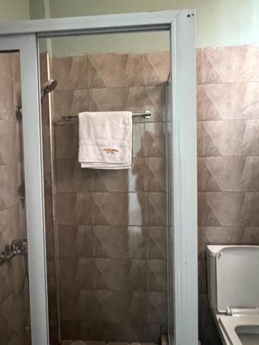 ein Handtuch, das an einer Duschtür im Bad hängt in der Unterkunft Jackie Grand Hotel in Cape Coast