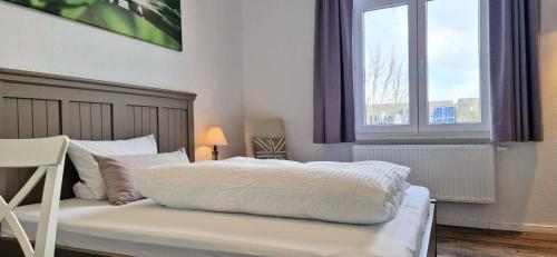 een slaapkamer met een wit bed en een raam bij Gästehaus Teerlings Hafen in Borkum