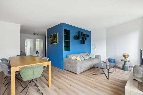 un salon avec un canapé et un mur bleu dans l'établissement Appartement elegant- Parc Saint Cloud, à Sèvres