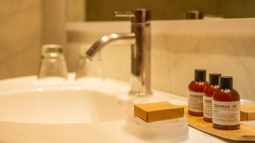 a bathroom sink with three bottles of soap and a sink at Alma Del Lago Suites & Spa in San Carlos de Bariloche