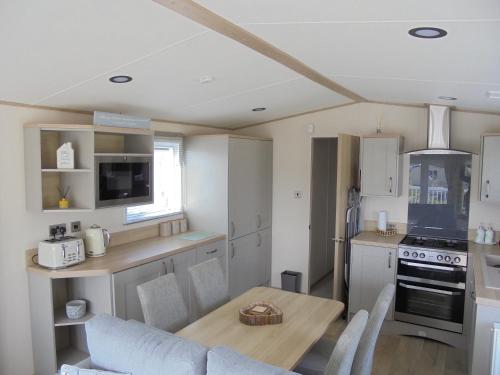 a kitchen with a table and a dining room at Kingfisher Windermere 6 Berth, Enclosed veranda, Close to site shop in Ingoldmells