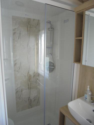 a bathroom with a glass shower with a sink at Kingfisher Windermere 6 Berth, Enclosed veranda, Close to site shop in Ingoldmells