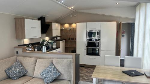 a living room with a couch and a kitchen at Cosy 3-Bed hot tub Lodge in Pr3 in Preston