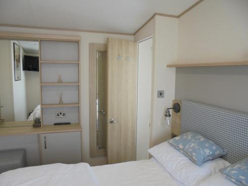 a bedroom with a bed and a bathroom with a shower at Kingfisher Windermere 6 Berth, Enclosed veranda, Close to site shop in Ingoldmells