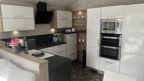 a kitchen with white cabinets and a stove top oven at Pet Friendly 2-Bed Lodge near Preston & Blackpool in Preston
