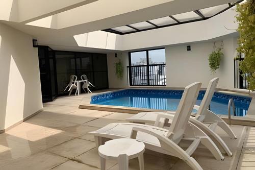 a pool with white chairs and a swimming pool at Get a Flat - 703 Luxo e Conforto - Ibirapuera in São Paulo