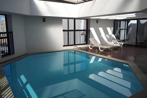 una grande piscina in un edificio con sedie di Get a Flat 909 - Conforto Ibirapuera a San Paolo