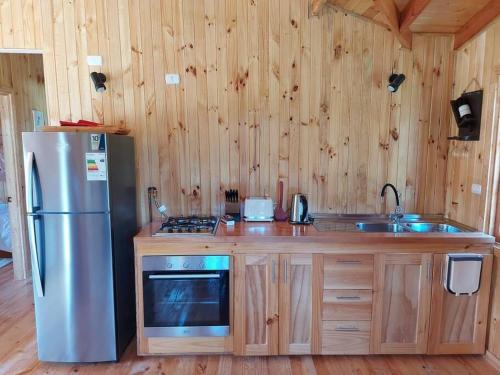 a kitchen with a stainless steel refrigerator and a sink at Cabaña Queltehue Cochamó in Cochamó