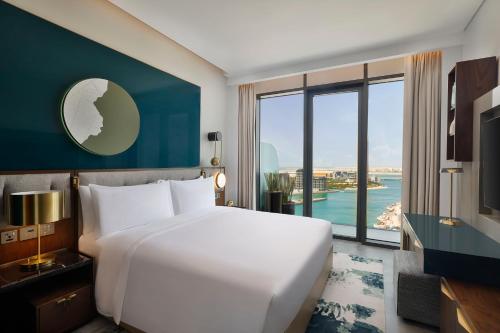 sypialnia z dużym białym łóżkiem i dużym oknem w obiekcie Conrad Bahrain Financial Harbour w mieście Manama