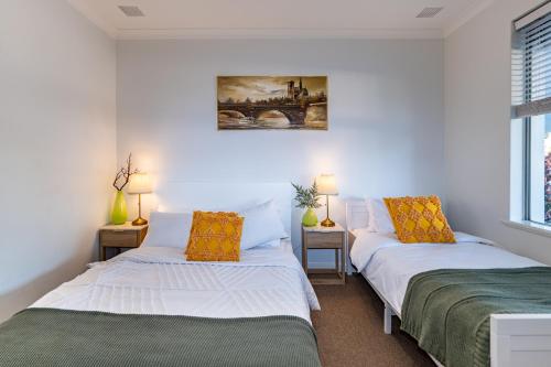 2 Betten in einem kleinen Zimmer mit 2 Lampen in der Unterkunft Cozy 5 bed House Nr Airport/DFO/Casino in Perth