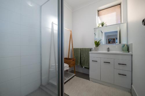 Baño blanco con lavabo y espejo en Cozy 5 bed House Nr Airport/DFO/Casino en Perth