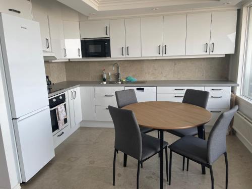 a kitchen with a table and chairs and white cabinets at Visby Snäck Lägenheter, Havsutsikt in Visby