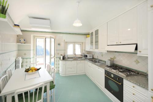 a kitchen with white cabinets and a table with a bowl of fruit at Donna Luisa Suite 9 Amalfi sea view - free parking in Scala