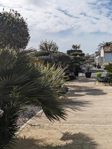 a park with palm trees and bushes and a building at L'Ile sous le Vent in Sainte-Marie-de-Ré