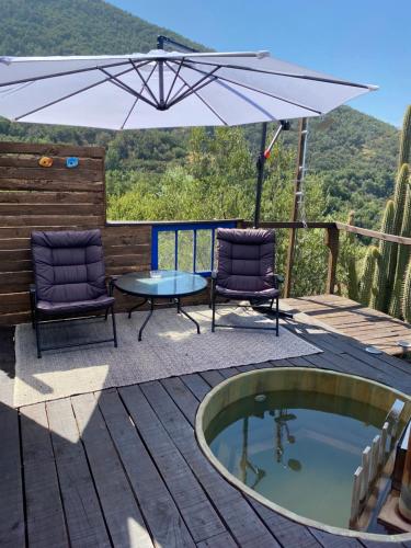eine Terrasse mit einem Whirlpool, 2 Stühlen und einem Sonnenschirm in der Unterkunft @alasaguas in San José de Maipo