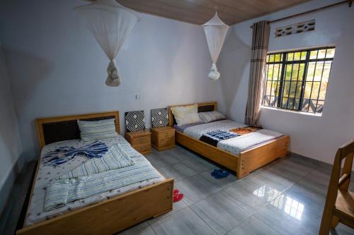 1 dormitorio con 2 camas y ventana en Akagera Neighbors, en Kabarondo