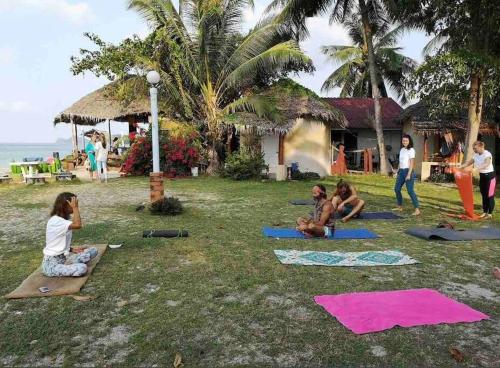 een groep mensen die yoga doen op het gras bij Sunset Serenity Cove in Ko Pha Ngan