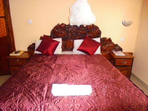 a bedroom with a large red bed with red pillows at White Rose Lodge in Livingstone