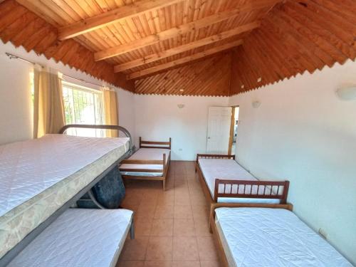 three beds in a room with wooden ceilings at Cabaña con jacuzzi, 7 personas. in Quillón