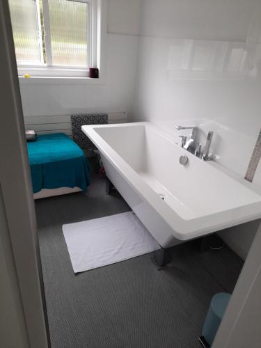 ein Badezimmer mit einem weißen Waschbecken und einem blauen Stuhl in der Unterkunft SERENITY in Bromley