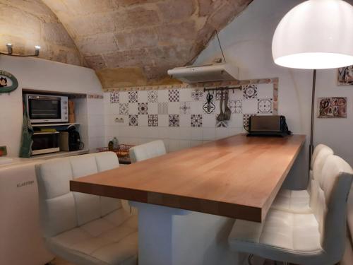 eine Küche mit einem Holztisch und weißen Stühlen in der Unterkunft Appartement cosy au cœur d'Uzès in Uzès
