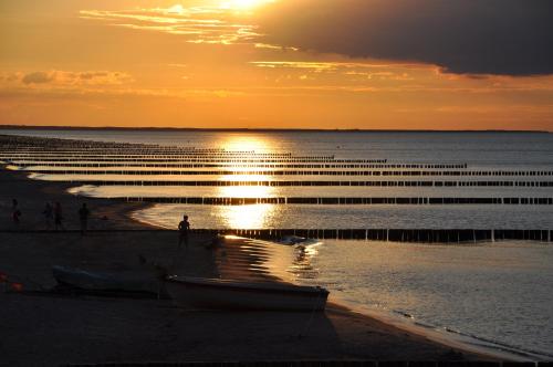 a beach at sunset with a boat on the shore at SEETELHOTEL Nautic Usedom Hotel & Spa das Hotel für Wellness & Genuss auf Usedom in Ostseebad Koserow