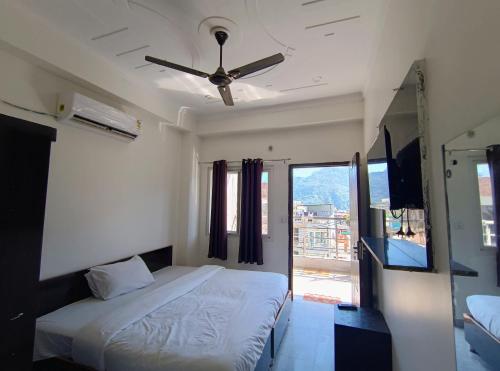 a bedroom with a bed and a ceiling fan at Hotel Aman in Rishīkesh