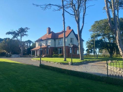 a house with a fence in front of a yard at The Old Vicarage NI B&B in Ballywalter