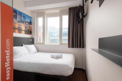 een kleine kamer met een bed en een raam bij easyHotel The Hague City Centre in Den Haag