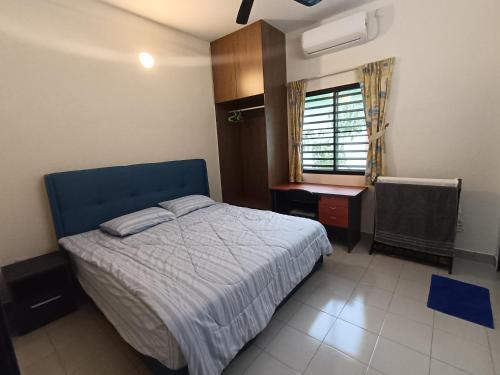 Schlafzimmer mit einem Bett, einem Schreibtisch und einem Fenster in der Unterkunft Lim Garden Homes in Balik Pulau
