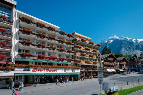 um grande edifício de apartamentos com uma montanha ao fundo em Hotel Bernerhof Grindelwald em Grindelwald