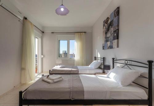 2 łóżka w sypialni z oknem w obiekcie Comfy Central Square Gem with Balcony w Kalamácie