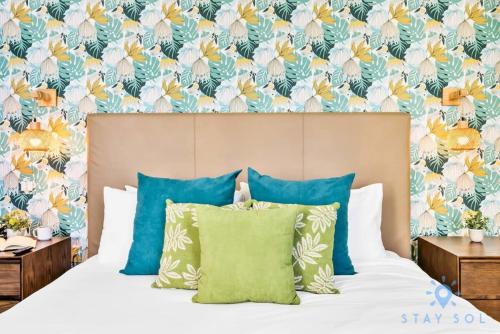 a bedroom with a bed with blue pillows and a floral wallpaper at Costa Hollywood - Worth Traveling - Rooftop Pool- Gym in Hollywood
