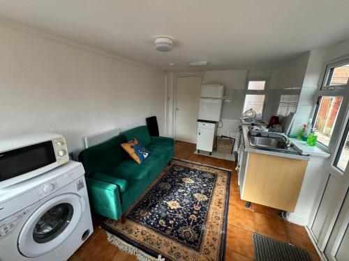 uma sala de estar com um sofá verde e uma máquina de lavar roupa em One Bedroom Flat with on premises parking em Walsall