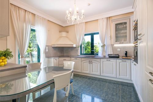uma cozinha com armários brancos e um lustre em Vouliagmeni Athenian Riviera Villa em Atenas