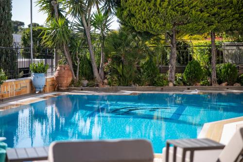 una grande piscina blu con sedie e alberi di Vouliagmeni Athenian Riviera Villa ad Atene