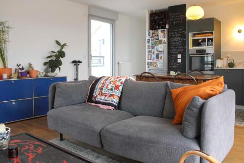 - un salon avec un canapé gris et un oreiller orange dans l'établissement Spacious cocoon with parking, à Aubervilliers