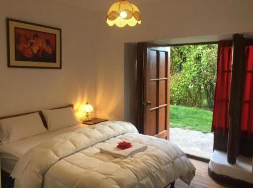 a bedroom with a white bed and a sliding glass door at El Jardín de Jeni in Cusco
