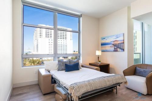 a bedroom with a bed and a chair and windows at Rooftop Pool- Gym - Hollywood Beach Broad - walk in Hollywood