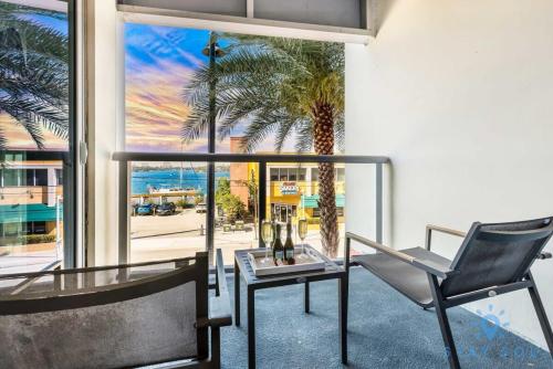 a room with a glass table and a chair and a palm tree at Apartment with Bay View Balcony - Pool - Up To 6 - Gym in Hollywood