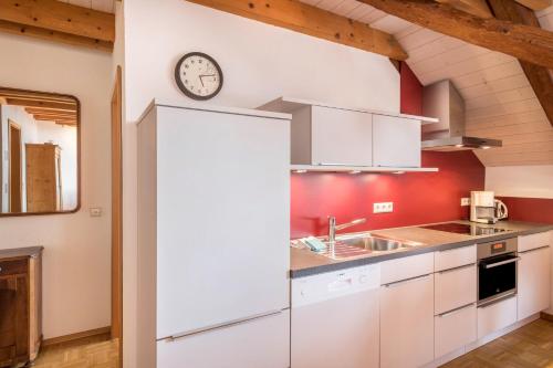 a kitchen with white cabinets and a clock on the wall at Obst- Ferienhof Ragg in Immenstaad am Bodensee