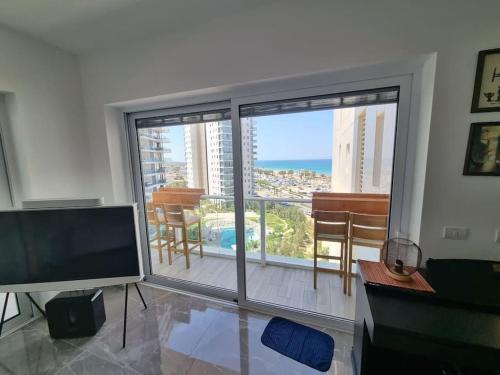 a living room with a flat screen tv and a large window at Beach front luxury apartment - managed building in H̱adera